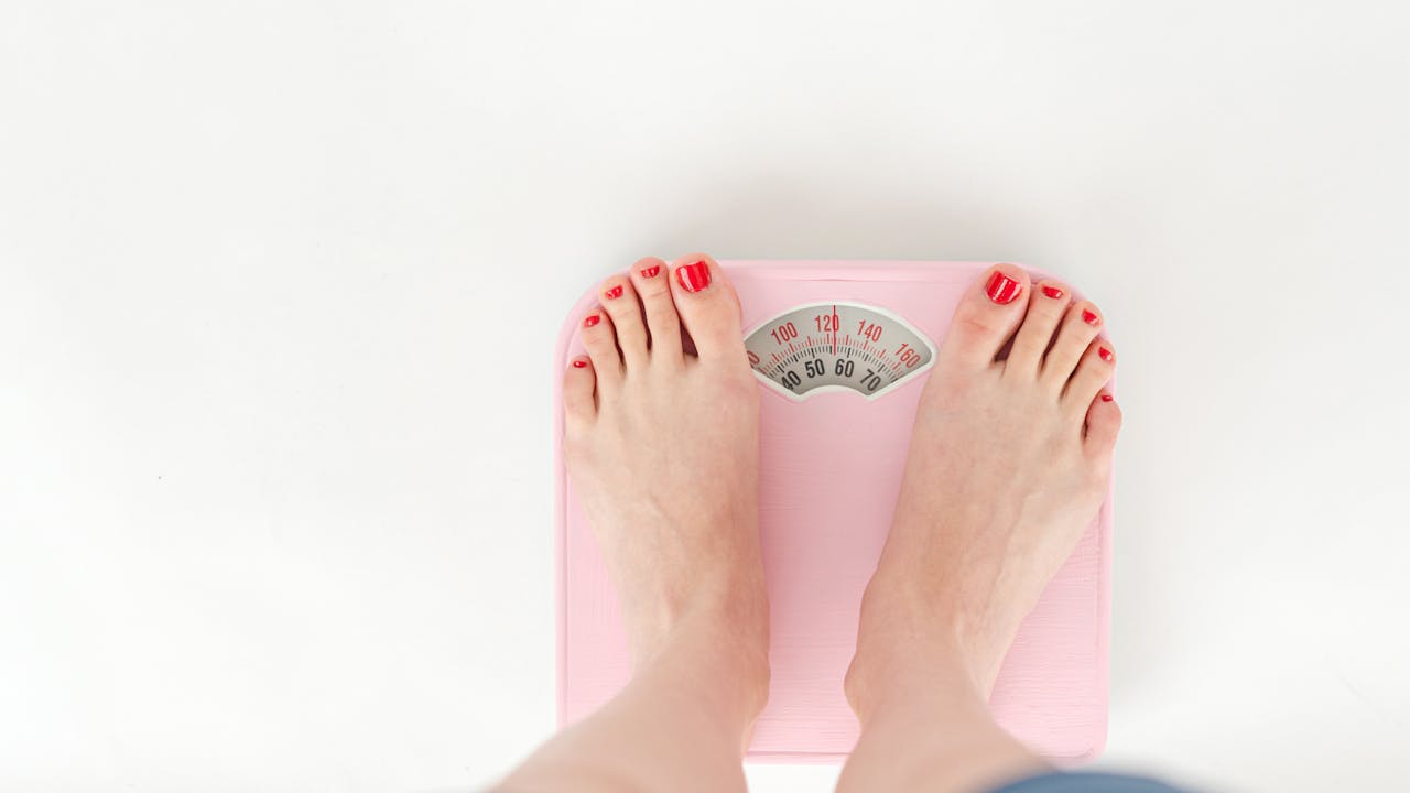 Person measuring their waist with a soft tape measure, tracking progress
