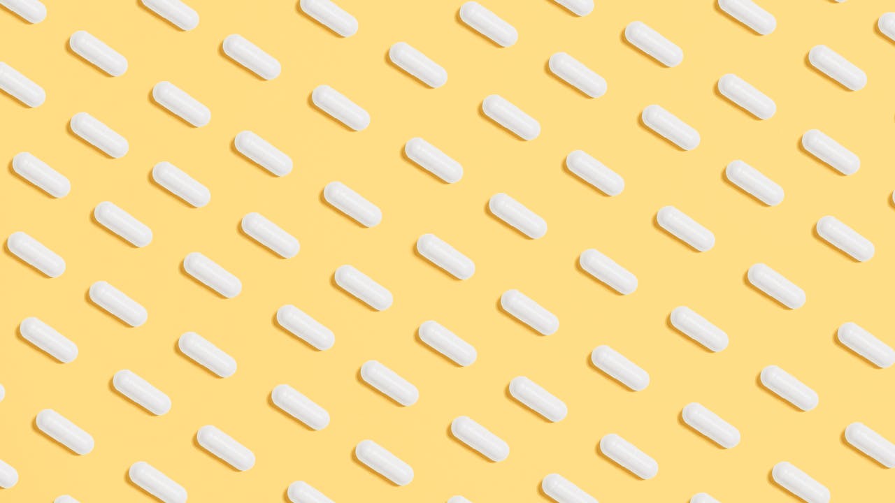 Oral supplement capsules and powder on a marble surface with clean minimal styling