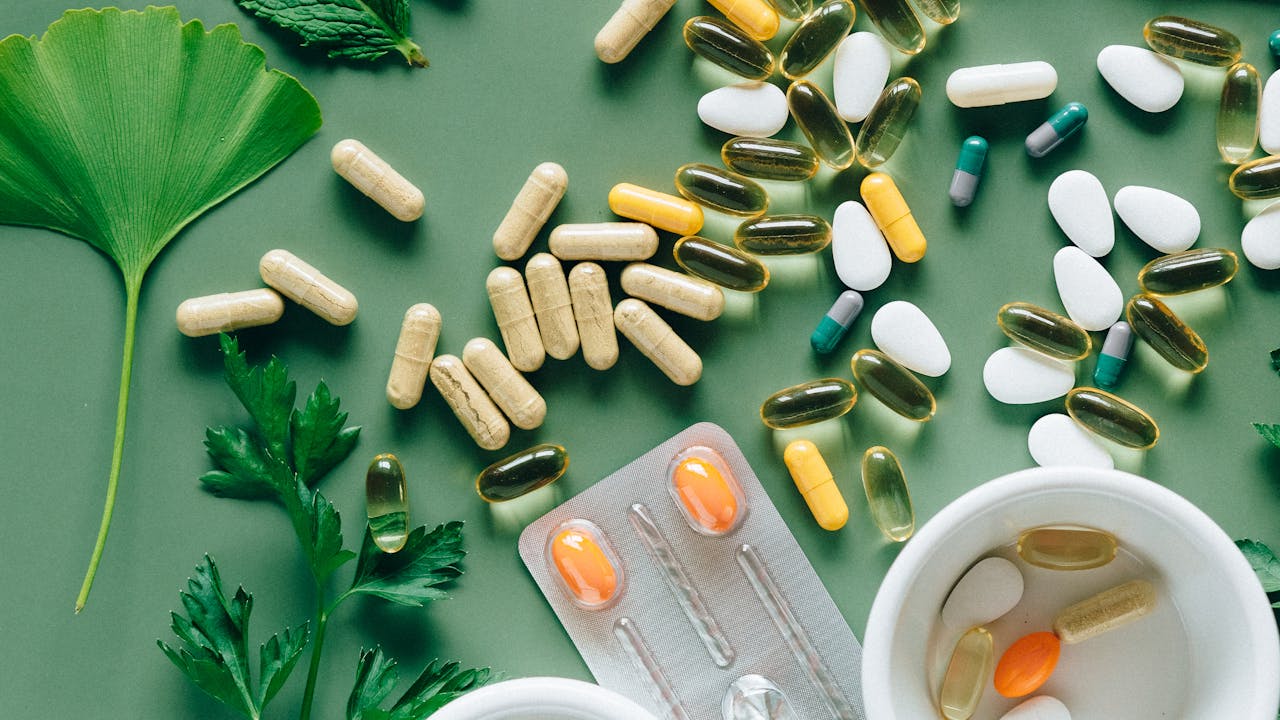 Hands holding supplement capsules over a clean white surface with natural light