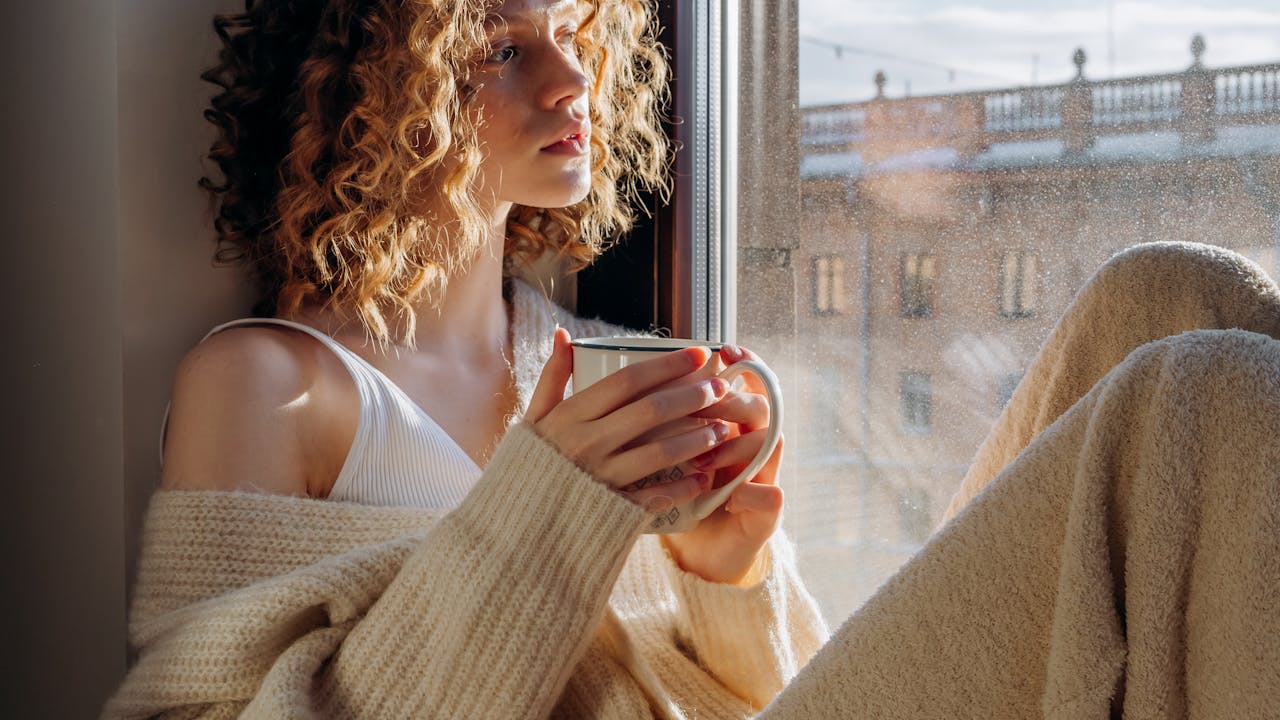 Person sitting calmly by a window with morning light, wellness and health lifestyle scene