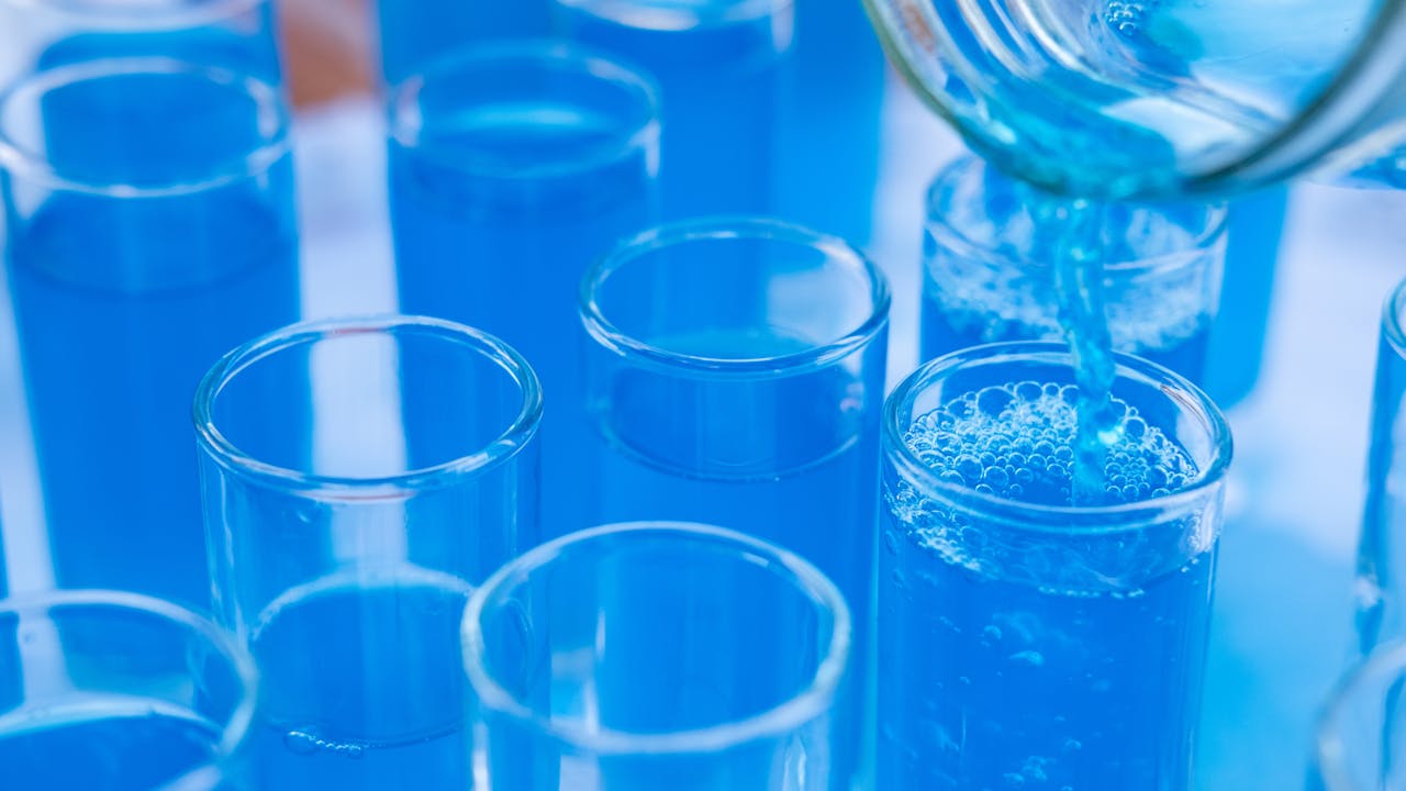Close-up of blue liquid in laboratory glass dropper bottles on white surface