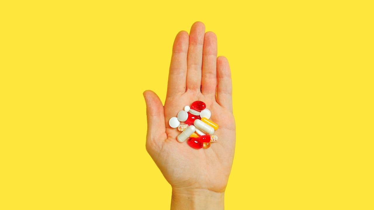 Close-up of supplement capsules and powders with a glass of water on a clean surface