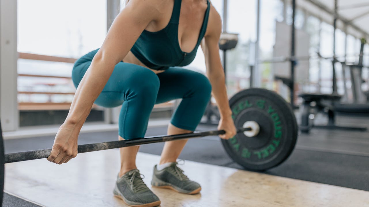 Woman doing resistance training with barbell in a gym setting