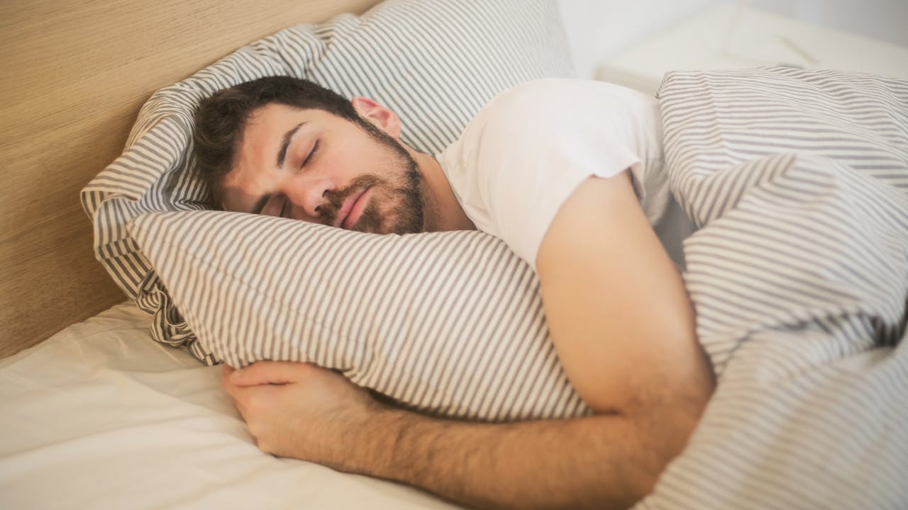 Person resting peacefully in bed, morning light through curtains, healthy sleep
