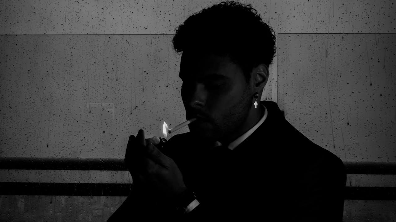 Man smoking a cigarette in a dimly lit setting